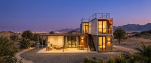 Finished container home in Sharjah at dusk with warm interior lighting and shaded terrace