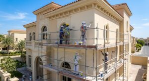 Workers on scaffolding painting a villa facade, an exterior job that raises painting contractor prices in Dubai